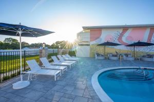 a swimming pool with white chairs and an umbrella at The Bentley Hotel Southampton in Southampton