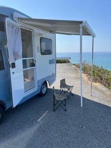 a camper with a table and a chair under a tent at ゲストハウス假穂 in Yoron