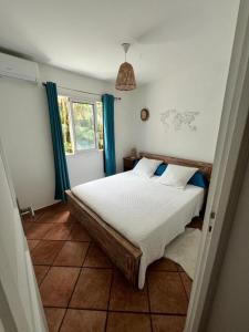 a bedroom with a large bed with blue curtains at L’anthurium in Saint-Paul