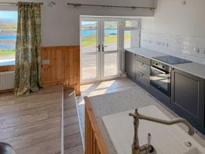 a kitchen with a sink and a large window at Post Office Lodge in Manish
