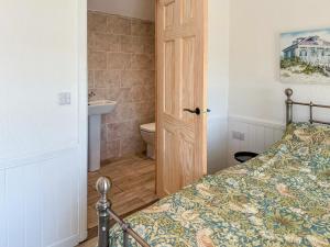 a bedroom with a bed and a bathroom with a toilet at Post Office Lodge in Manish +3 photos