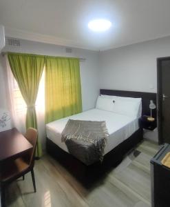 a bedroom with a bed and a chair and a window at Oloks Guest Inn in Francistown