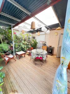 a patio with a table and chairs on a wooden deck at L’anthurium in Saint-Paul