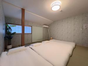 two beds in a small room with a window at 和居 琉璃 和を感じるレイアウトで心も体も休まる宿 in Wada