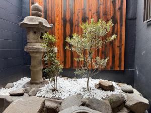 a garden with two trees and a stone fountain at 和居 琉璃 和を感じるレイアウトで心も体も休まる宿 in Wada
