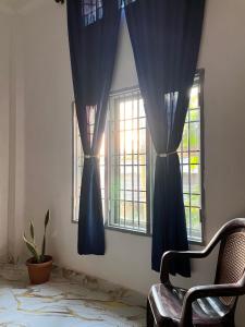 a room with blue curtains and a chair and a window at Dharitry Homestay Majuli in Mājuli Island