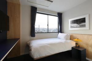 a bedroom with a bed and a large window at evo Hotel Hakuba in Hakuba