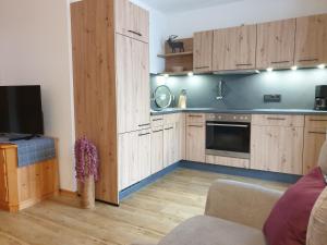 a kitchen with wooden cabinets and a couch and a tv at Gästehaus Bergblick in Wallgau