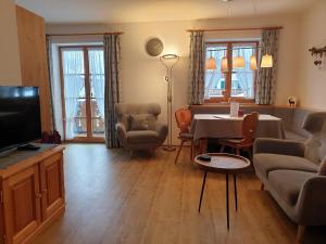 a living room with a couch and a table and a tv at Gästehaus Bergblick in Wallgau