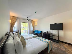 a hotel room with two beds and a flat screen tv at RMH Le Belhamy Beach Resort in Hoi An