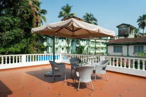 a patio with a table and chairs and an umbrella at Quinta da Praia by Semper Felix in Calangute