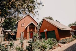 a red brick house with a green garage at La Rona Hospitality Services in Rustenburg