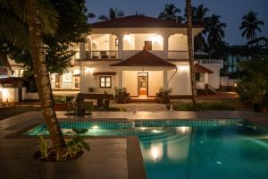 a villa with a swimming pool in front of a house at Quinta da Praia by Semper Felix in Calangute
