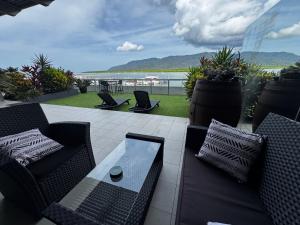 a patio with couches and chairs and a view of the ocean at Cairns Waterfront Luxury at Harbourlights in Cairns