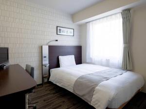 a bedroom with a bed and a desk and a window at Comfort Hotel Nara in Nara