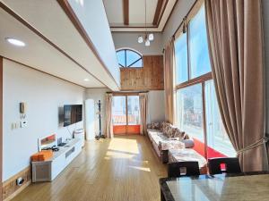 a living room with a couch and a large window at Sanbangsan Hot Spring Pension in Seogwipo