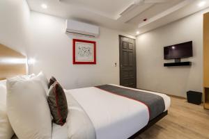 a bedroom with a white bed with a tv on the wall at Townhouse Derawal Nagar in New Delhi