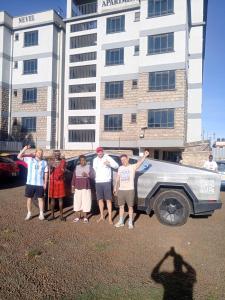 a group of people standing in front of a car at Primestay Suites in Eldoret