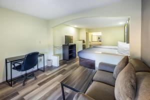 a hotel room with a bed and a desk and a couch at Super 8 by Wyndham Jackson MS Near the Fairgrounds in Jackson