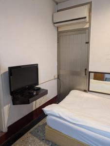 a small room with a bed and a flat screen tv at Golden Dragon Hotel in Houlong