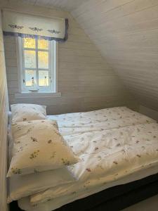an unmade bed in a room with a window at Cabin by the lake in Sveio
