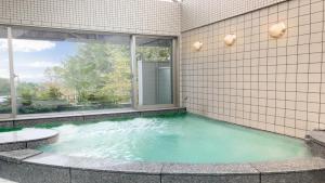 a swimming pool in a building with a large window at Livemax Resort Yatsugatake Kogen in Hokuto