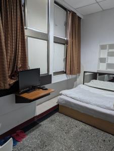 a bedroom with a bed and a desk with a computer at Golden Dragon Hotel in Houlong