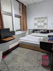 a bedroom with a bed and a desk with a computer at Golden Dragon Hotel in Houlong