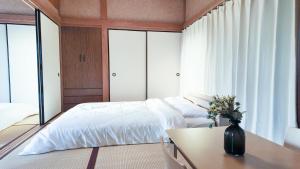 a bedroom with a bed and a table with a vase on it at FUNAKATA MINA House in Tateyama