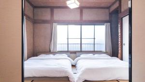 a mirror reflecting two beds in a room with a window at FUNAKATA MINA House in Tateyama