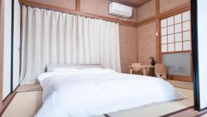 a bedroom with a white bed and a window at FUNAKATA MINA House in Tateyama