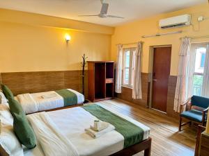 a hotel room with two beds and a chair at The Mountain House in Pokhara