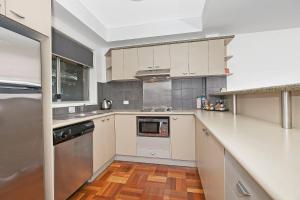 a kitchen with white cabinets and a wooden floor at Comfort Inn & Apartments Northgate Airport in Brisbane