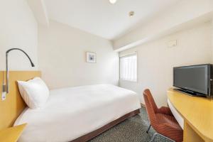 ein Hotelzimmer mit Bett, Schreibtisch und Fernseher in der Unterkunft Hotel Sunflex Kagoshima in Kagoshima