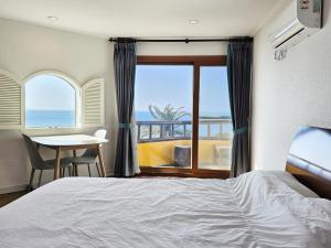 a bedroom with a bed and a view of the ocean at Tteuribada Pension in Seogwipo