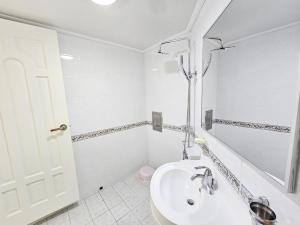a white bathroom with a sink and a mirror at Tteuribada Pension in Seogwipo +27 photos