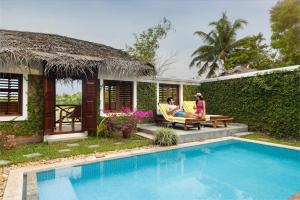 two people sitting in chairs next to a swimming pool at Coconut Lagoon Kumarakom - A CGH Earth Experience in Kumarakom