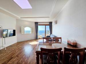 a living room with a table and chairs and a couch at Tteuribada Pension in Seogwipo