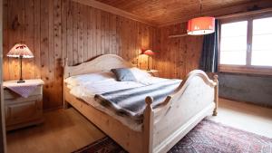 a bedroom with a white bed in a wooden wall at Rustico Pagrüeg - Swiss Alpine Charm 1-5 Pers in Klosters Serneus