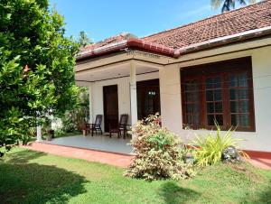 a house with a porch and chairs in the yard at Oshi villa in Hikkaduwa