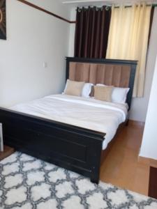 a bedroom with a bed with a black headboard and a rug at Belaire BnB Ruaka 1 in Nairobi