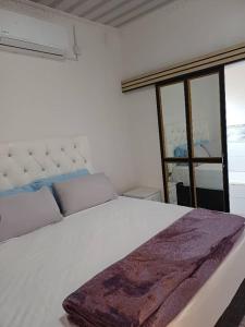 a white bed with a purple blanket on top of it at Yadah Accommodations in Lothlekane