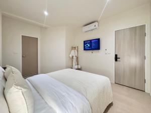 a white bedroom with a bed and a tv at Quies Hotel in Krabi