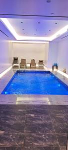 a large swimming pool in a building with chairs at فندق حياة تاون حقل in Ḩaql