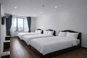 two beds in a hotel room with a window at Laimeront Dalat Hotel & Apartment in Da Lat +97 photos
