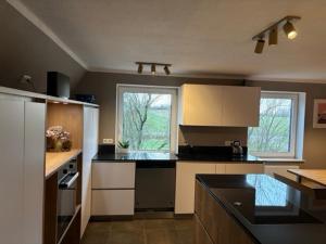 a kitchen with black counter tops and white cabinets at Schwalbennest Flensburger Förde in Westerholz