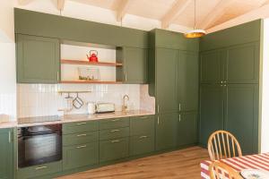 a green kitchen with green cabinets and a table at Just Like Home - Casa da Tuca in Moledo