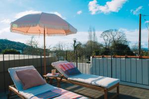 two chairs and an umbrella on a patio at Just Like Home - Casa da Tuca in Moledo