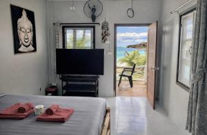 a bedroom with a bed with a television and a view of the ocean at Last Hammock Beach Resort in Baan Khai