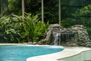 a swimming pool with a waterfall in a yard at Rainforest Escape with Pool & Mountain Views in Caravonica +32 photos